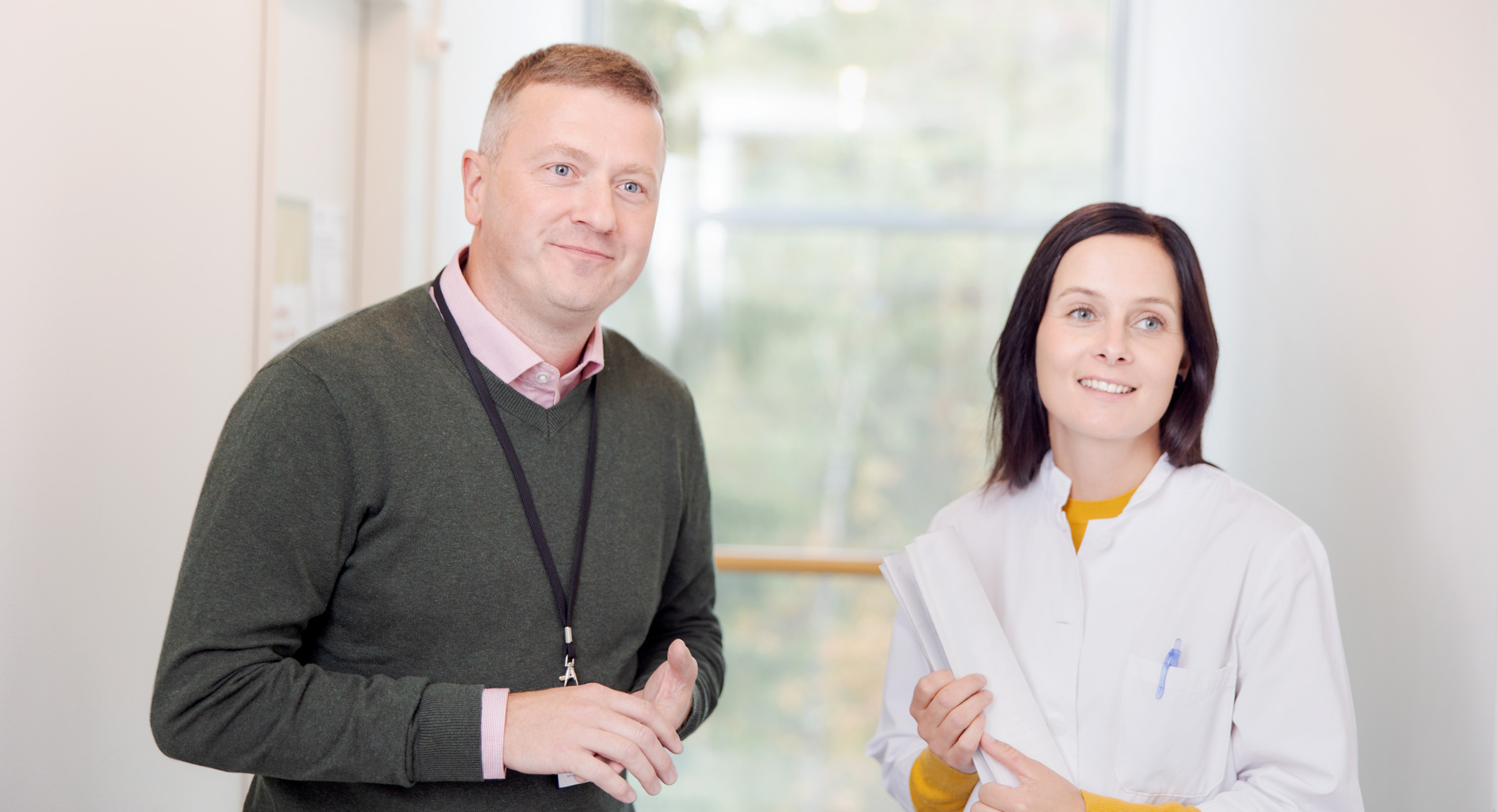 Sosiaalityöntekijä ja lääkäri käytävällä vierekkäin.