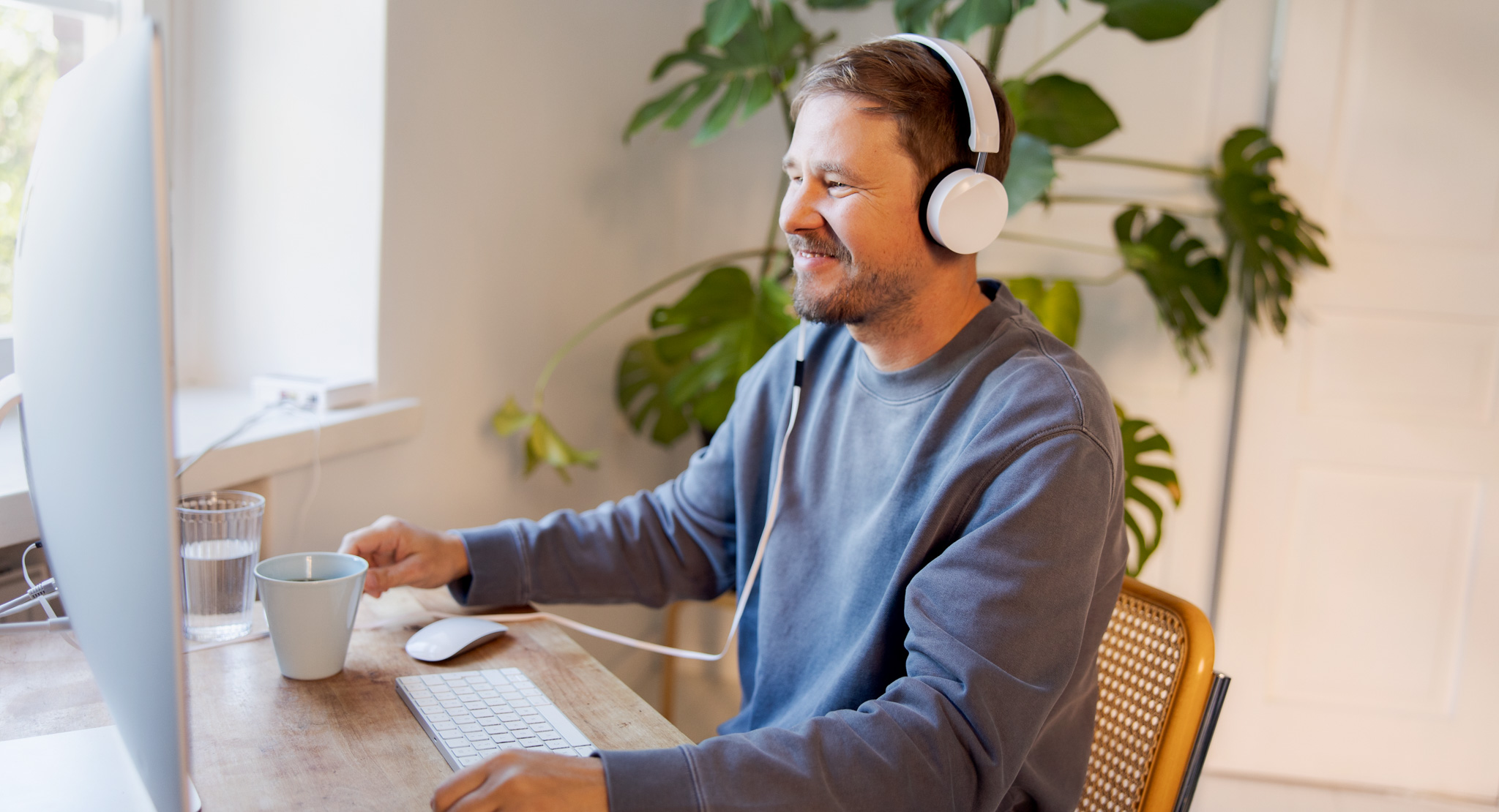 Hymyilevä mies tietokoneella.